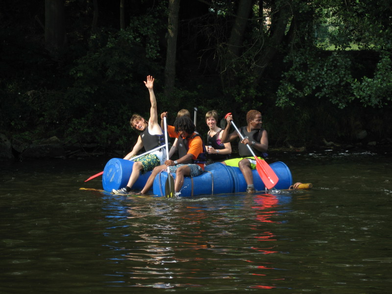 Groep mensen aan het pedellen op een zelfgemaakt vlot